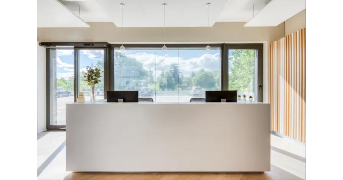 A reception area with a white desk with a large open window behind it